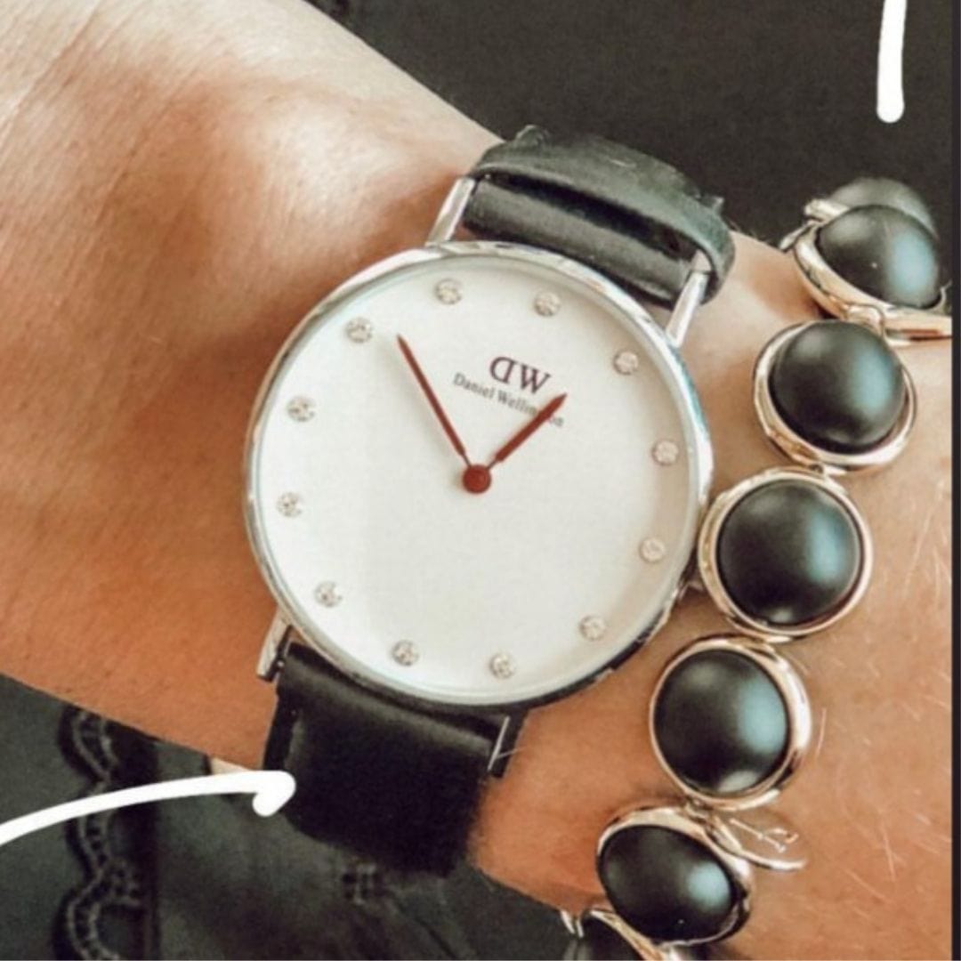 A wrist wearing a stacked gemstone bracelet by Brett Lauren, paired with a classic silver watch, creating a stylish combination of elegance and functionality.